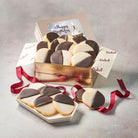 Dulcet gold birthday gift tin filled with gourmet black and white cookies featuring chocolate and vanilla icing, a Happy Birthday cupcake-themed lid, branded tissue paper, and burgundy ribbon.