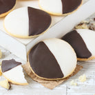 Close-up of Dulcet's classic black and white cookies featuring soft, golden cookie bases topped with half chocolate and half vanilla icing.