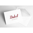 White Dulcet Gift Baskets greeting card featuring the burgundy brand logo, displayed alongside a matching white envelope for personalized gift messages.