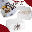 Dulcet premium white gift box shown open with individually wrapped gourmet brownies and assorted baked treats, alongside elegant packaging, branded tissue paper and a silver satin bow.