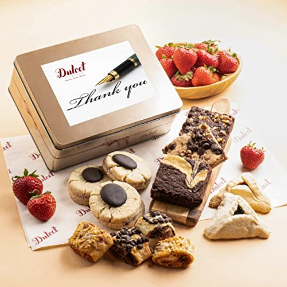 Dulcet gold Thank You gift tin with fountain pen artwork, displayed alongside gourmet brownies, blondies, chocolate-topped cookies, hamantaschen, assorted rugelach and strawberries.