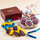 Dulcet Easter gift box featuring blue and yellow chick cookies, yellow and chocolate iced cookies, rainbow sprinkle cookies, and pastel Easter eggs.