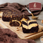 Assorted gourmet chocolate brownies featuring cream cheese swirl brownies, chocolate chip-topped treats and nut-topped brownies on a wooden serving board.