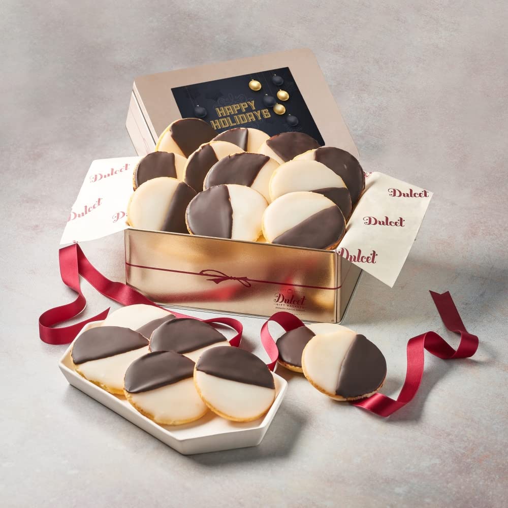 Dulcet gold holiday gift tin filled with chocolate and vanilla iced black and white cookies, featuring a Happy Holidays lid, branded tissue paper, and burgundy ribbon.