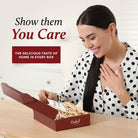 Smiling woman opening a burgundy Dulcet gift box filled with drizzled bakery treats and a personalized note, highlighting thoughtful gifting.