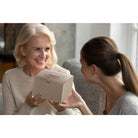 Smiling mother receiving a Dulcet gift box from her daughter at home, capturing a thoughtful gift-giving moment.