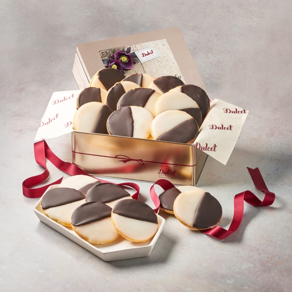 Gold Dulcet gift tin filled with black and white cookies, with more cookies on a tray and red ribbon.