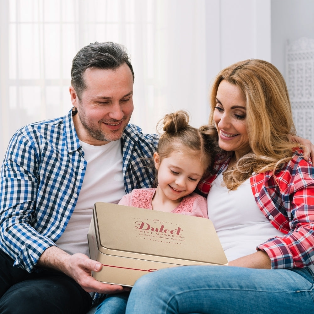 Parents and their young daughter smiling together while holding a Dulcet bakery gift box.